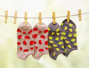 Macro detail view of strong wooden clothes pegs holding colorful patterned socks on a line