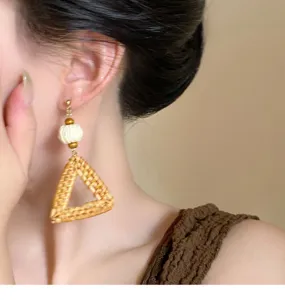 Λεπτομερές κοντινό πλάνο ενός κομψού σκουλαρικιού από ψάθα με τριγωνικό σχεδιασμό.