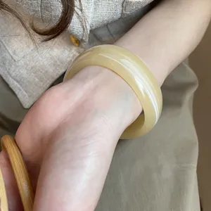 Primer plano de brazalete de resina beige minimalista en la muñeca, detalle estético vintage.