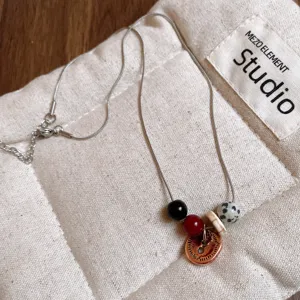 Primo piano della collana in acciaio inossidabile con pendente a bottone e perle.