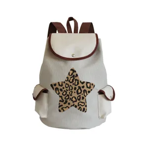 Detailed view of canvas backpack with brown trim, side pockets, and stylish leopard star.