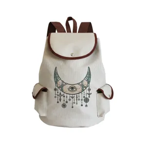 Canvas backpack detail showing crescent moon eye print, brown leather trim, and front pocket design.