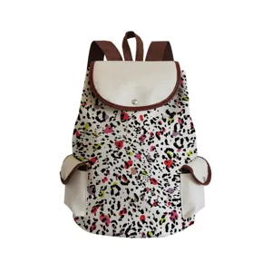 Canvas backpack detail showing abstract eye print pattern, brown straps and dual side pockets.