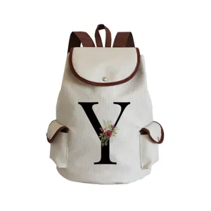 Detailed view of canvas backpack featuring floral letter Y print and brown leather trim.