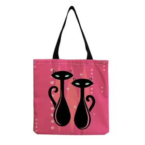 Detail view of a stylish pink canvas tote bag featuring retro black cat print and black handles.