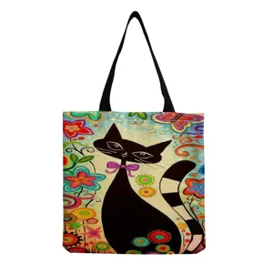 Canvas tote bag detail showcasing artistic black cat and colorful floral print pattern.