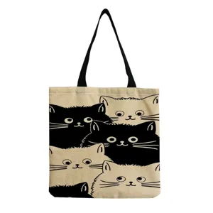 Detailed view of the canvas tote bag featuring cute cartoon cat prints and sturdy handles.