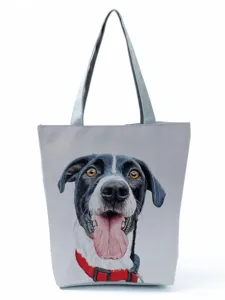 Close-up detail of grey canvas tote bag featuring cute dog print and sturdy red collar handle.