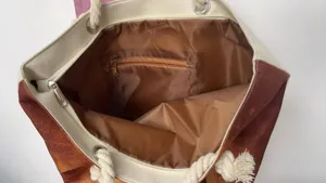 Détail intérieur du sac cabas en toile avec doublure marron, poche zippée et poignées robustes.
