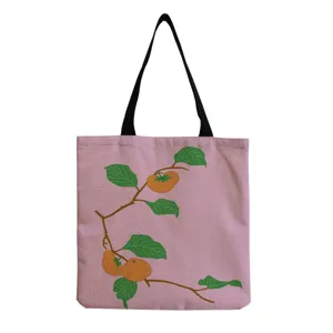 Detailed view of the pink canvas tote bag featuring a charming persimmon branch print and straps.