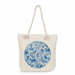 Detalle cercano del bolso de lona con estampado floral azul y asas de cuerda gruesa.