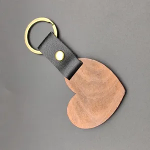 Houten hartvormige sleutelhanger met zwarte lederen band en messing ring. Detailweergave.