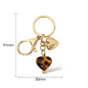 Détail de porte-clés doré avec pendentif cœur en métal et breloque écaille de tortue.
