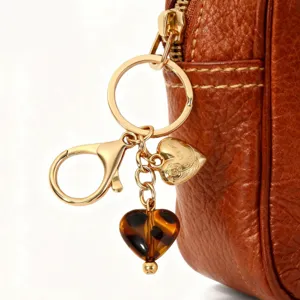 Charm de sac en cuir marron avec anneau doré, pendentif cœur léopard et détail métal.