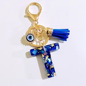 Blue initial T letter keychain with gold chain, leather tassel and evil eye charm detail.