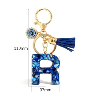 Blauwe hars letter R sleutelhanger met boze oog bedel, kwastje en gouden hardware.