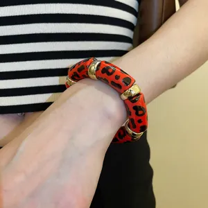 Close-up detail shot of a bold red leopard print acrylic elastic bracelet with gold rings.