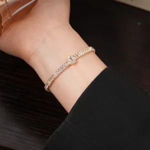 Detailed close-up view of the elegant gold-plated square zirconia tennis bracelet worn on the wrist.