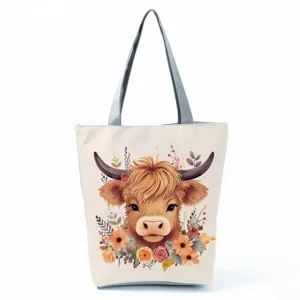 Close-up of the highland cow print tote bag with floral art, sturdy grey handles and details.