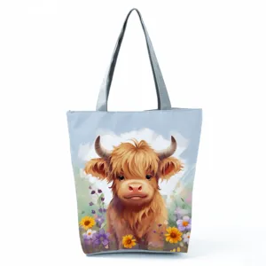 Close-up detail showing the cute highland cow print and durable grey handle of the canvas tote bag.