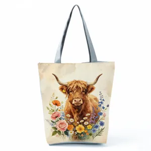 Highland cow print canvas tote bag detail, featuring watercolor floral design and sturdy gray handles.