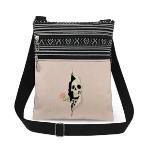 Dettaglio in primo piano della borsa a tracolla in tela con tasche con zip e stampa teschio.