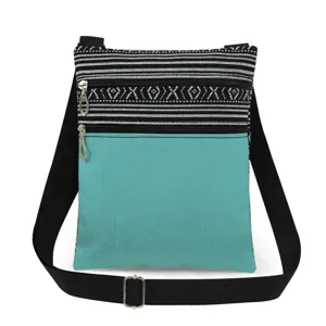 Detailopname van canvas schoudertas met zwart-witte strepen en turquoise zak.