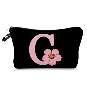 Detalle de bolsa cosmética negra con letra C rosa y estampado floral y cierre de cremallera.