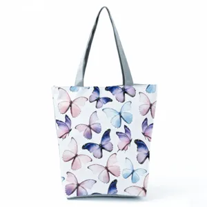 White shoulder bag with watercolor butterfly print, featuring sturdy grey straps and detail.