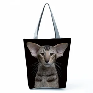 Detail view of a black canvas tote bag featuring a cute cat print and long shoulder straps.
