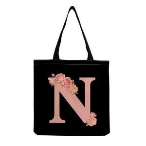 Gros plan sur le sac fourre-tout noir avec lettre rose N et impression de roses aquarellées.