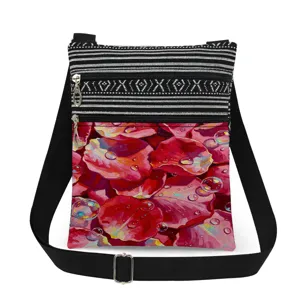 Detailed view of double zipper floral crossbody bag with rose petal print and black strap.