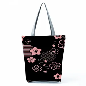 Λεπτομέρεια τσάντας shopper με τύπωμα ανθών κερασιάς σε μαύρο ύφασμα με ροζ μοτίβο.