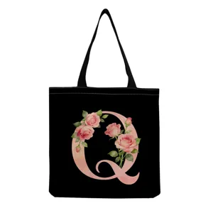 Détail de sac cabas en toile noire avec un superbe motif floral rose aquarelle lettre Q.