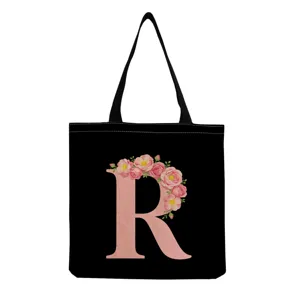 Détail du sac cabas en toile noire avec un bel imprimé lettre R florale rose et anses.