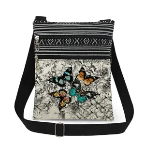 Vista detallada del bolso cruzado de lona con estampado de mariposas y cremalleras.