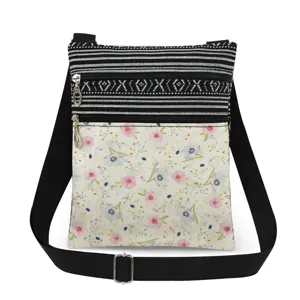 Detail view of the floral printed canvas crossbody bag featuring dual zippers and adjustable black strap.