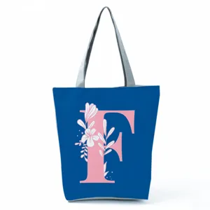 Close-up detail of the blue tote bag featuring pink letter F and white floral print.