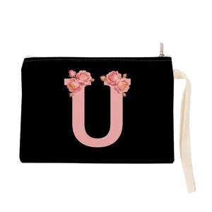 Black cosmetic bag with pink floral letter U design, portable canvas pouch with wrist strap.
