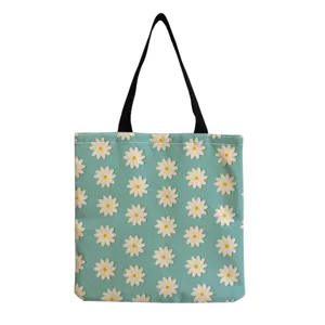 Detailansicht der blauen Stofftasche mit weissem Bluemchenmuster und schwarzem Tragehenkel.