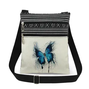 Vista detallada del bolso cruzado de lona con estampado de mariposa azul y cremalleras.