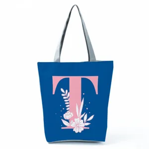 Detailed view of the blue canvas tote bag featuring a pink letter T and floral print design.
