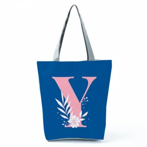 Close-up detail of the blue canvas tote bag featuring a pink letter Y and white floral print.