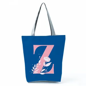 Blue tote bag detail featuring a pink letter Z and floral print with sturdy grey handles.