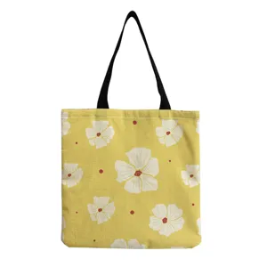 Detaillierte Ansicht der gelben Canvas-Tasche mit Blumenmuster und praktischen schwarzen Henkeln.