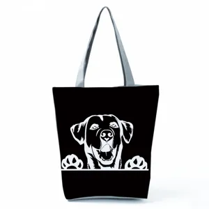 Vista dettagliata della borsa shopper nera in tela con stampa di cane bianco e manici grigi.