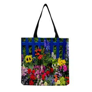Gros plan sur le motif de fleurs de jardin colorees sur le sac en toile avec anses noires.