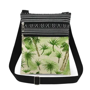 Close-up of lightweight canvas crossbody bag with tropical palm tree print and dual zippers.