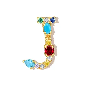 Detailed shot of letter J pendant, colorful cubic zirconia inlay on copper base accessory.