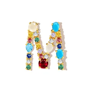 Detail view of gold plated M letter pendant encrusted with colorful cubic zirconia stones.